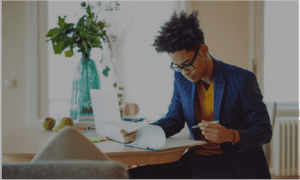 Business professional sitting at home looking over papers on clipboard