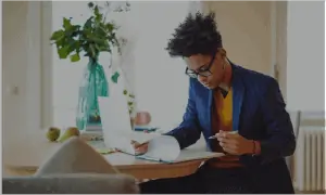 Business professional sitting at home looking over papers on clipboard