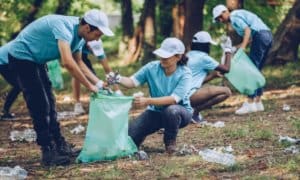 adults helping pick up trash in park