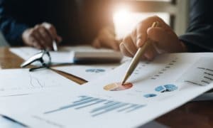 Business professionals in suits meeting while pointing at charts with pen