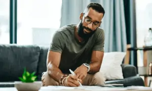 Man sitting on couch writing on papers