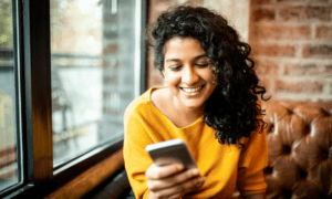 Women smiling while on phone sitting on couch