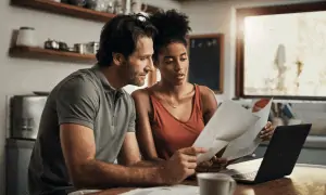 Couple looking over papers while working on computer at home