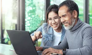 Father and daughter smiling while working on computer