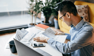 Man working at desk reviewing financials with calculator