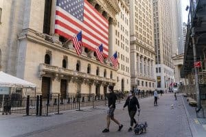 New York City, NY, USA - April 6, 2020: ‘Fearless Girl’ Statue in front of the Stock Exchange from the Wall Street deserted because of the COVID-19 pandemic, like a symbol of the coming economic depression. Just a few people wearing protective masks walking dogs on the empty street.