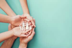 Adult and children hands holding paper family cutout, family home, foster care, homeless charity support concept, family mental health, international day of families