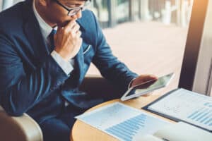 Businessman working and using Digital Tablet new business project finance investment at coffee cafe - to know acquisition financing blog