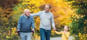 Elderly father adult son and grandson out for a walk in the park - long term care