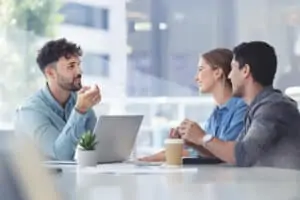 Financial advisor with couple explaining options. The agent is using a computer. Couple are casually dressed. They sitting in an office and are discussing something with the agent.