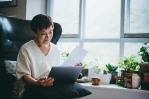 woman looking over a paper form and her computer