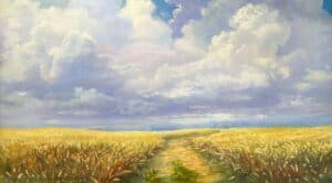 an unpaved road through a field against a cloudy sky