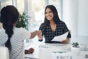 Shot of two young businesswomen shaking hands in a modern office